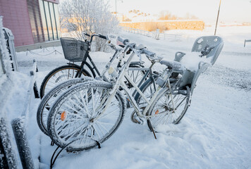 Obraz premium Snow covered bicycles parked on street in winter city of Finland in cold morning