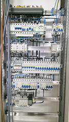 Open industrial electrical cabinet with circuit breakers, contactors and structured wiring. Complex power control system installed on DIN rails