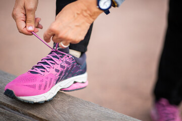 Woman tying pink running shoes before exercise outdoors