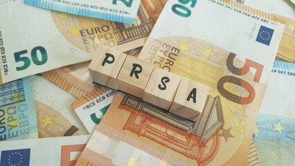 PRSA acronym made of wooden letter cubes on pile of Euro banknotes. Personal Retirement Savings Account