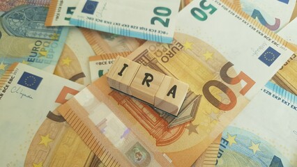 IRA acronym made of wooden letter cubes on pile of Euro banknotes. Individual Retirement Account