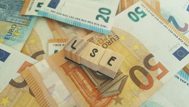 LSE acronym made of wooden letter cubes on pile of Euro banknotes. London Stock Exchange