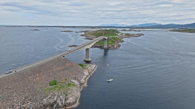 Aerial view of the Atlantic Road (Atlanterhavsveien) in Norway, Norwegian causeway leading toward Storseisundet Bridge over calm gray sea and skerries . Drone view tracks forward, opening the island.
