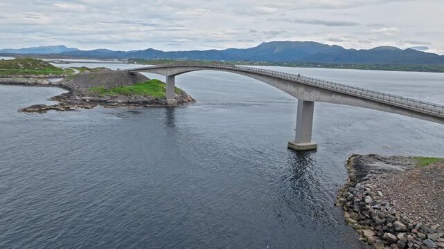 Aerial view of the Atlantic Road (Atlanterhavsveien) in Norway, Norwegian bridge arch rising above dark water and rock armor on both sides . 
