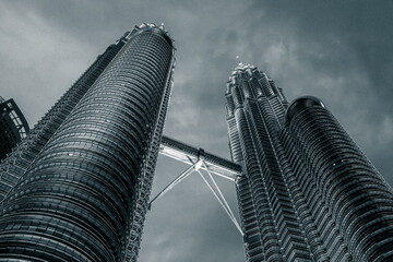 Towers in Kuala Lumpur, Malaysia, photographed from below at dusk with skybridge illuminated – iconic modern skyscrapers and architectural landmark © Marco