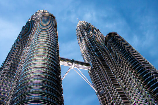 Skyscrapers captured at dusk from a low angle &ndash; illuminated modern skyscrapers with skybridge and blue sky backdrop