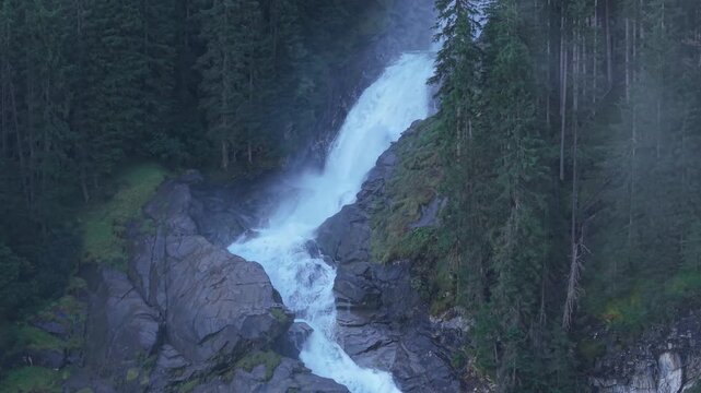 View from above of water flowing down the mountain among the trees. Aerial footage of the Krimml Waterfall in the middle of the forest, Austrian Alpine natural landscape