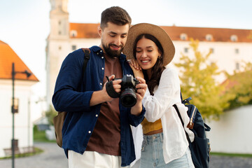 Happy couple smiling while checking photos on camera, walking in the city, travelling together during vacation © Home-stock