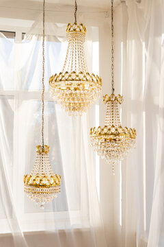 The design lamp chandelier on the roof of house near window.Expensive interior. Large electric chandelier made of transparent glass beads. Luxury old vintage chrystal chandelier