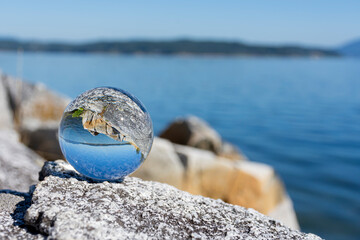 A serene image of a photographic lens ball reflecting the inverted image of the Pacific Ocean on Vancouver Island. 