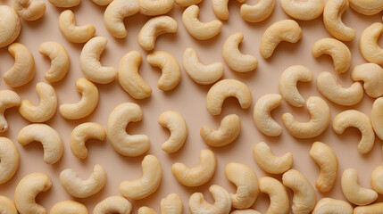Close-up of raw cashew nuts arranged on a warm yellow background.
