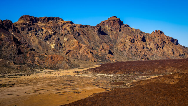 Vast volcanic mountain landscape under a clear blue sky with rugged terrain in Teide National Park