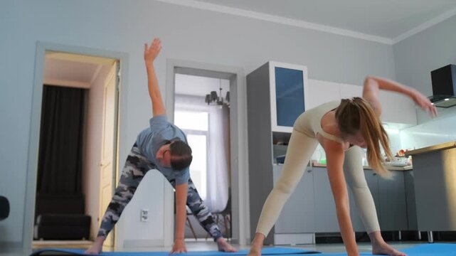 Woman doing yoga at home -  performing triangle pose with extended arm upward. Yoga training for stretching body -  improving posture -  flexibility and balance.