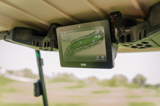 Golf cart GPS display mounted overhead showing course layout and distance to the hole on a sunny day