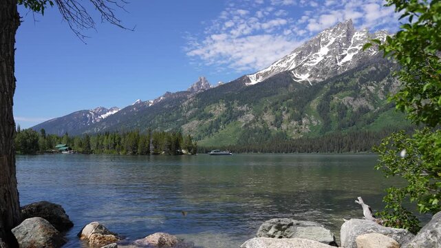 Beautiful super wide shot of a tour boat passing by on Jenny Lake in Grand Teton National Park, Wyoming.