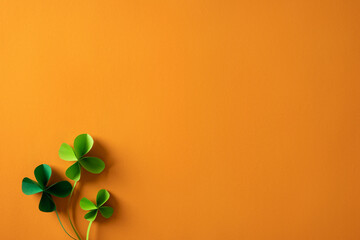Obraz premium Bright orange background features vivid green shamrocks to convey festive St Patrick's Day mood, perfect for greeting cards, promos, and seasonal content celebrating luck, Irish heritage, and spring