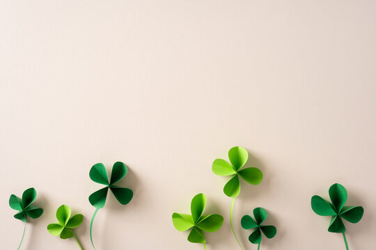 Shamrock leaves in vibrant green rise against a soft beige backdrop, evoking St Patrick Day celebration and luck. A fresh seasonal motif suitable for greeting cards banners and festive promotions