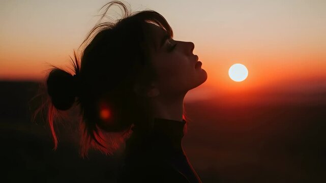 Cinematic Silhouette of Young Woman at Sunset, Woman Enjoying Golden Hour Outdoors, Moody Profile Portrait of Beautiful Female with Hair Bun against Orange Sun