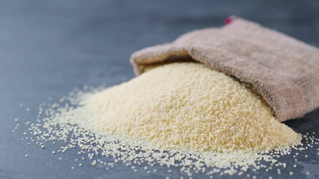 couscous in sack on a dark kitchen table. basmati rice spilled out of the bag a dark kitchen table.
couscous in sack on a black marble background. Organic couscous rice are scattered out of the bag. 