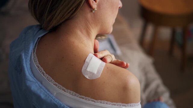 Woman applying estrogen patch during hormone therapy. Rear view.