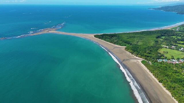 Smooth orbit drone shot around the Whale Tail sandbar in Uvita showing the tropical beach, Pacific Ocean and iconic coastal formation.