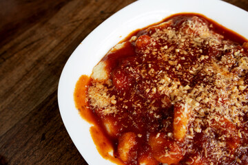 A portion of gnocchi in tomato sauce topped with cheese inside a white bowl, photographed from top to bottom