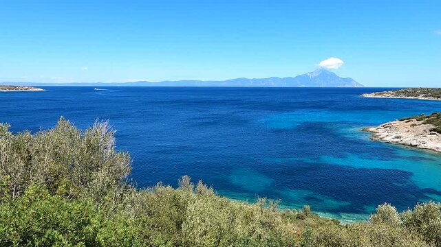 A quick view of Mount Athos' peak wrapped in clouds from Sithonia, the blue clear sea, a windy day and a transparent atmosphere after a summer rain