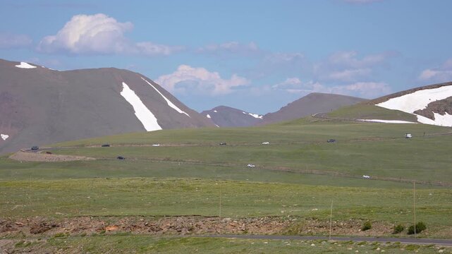 Beautiful scenic view of mountains in the background as a car drives in a zig-zag pattern along Trail Ridge Road in Rocky Mountain National Park, Colorado