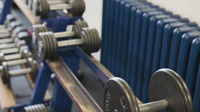 Man picks up sports equipment in form of heavy dumbbells stacked in gym. Special weights help harmoniously develop muscles strengthening health