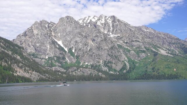 Tour boat cruising in the middle of Jenny Lake, Wyoming, surrounded by the dramatic peaks of Grand Teton National Park.