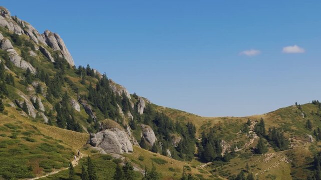 Wide view of Ciucas mountains rock slopes with distant hikers