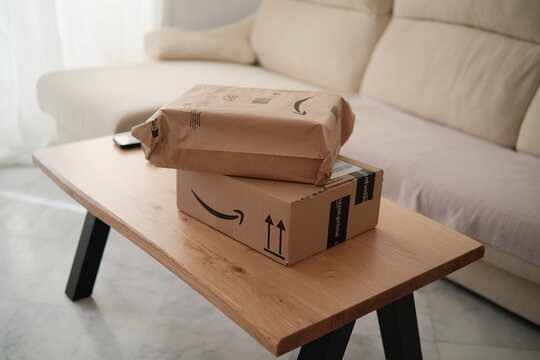 Alicante, Spain - February 02, 2026: Two Amazon delivery packages with Amazon logo on wooden table in a cozy living room