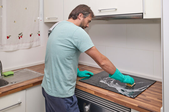 Wiping electric cooktop with sponge and cloth during home cleaning