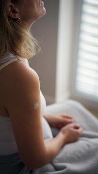 Woman applying estrogen patch during hormone therapy. Rear view.