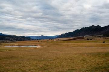 Obraz premium Grass Valley sheep farms and pond in Garfield County western Colorado under complex winter cloudscape.
