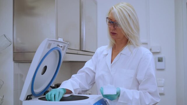 Senior scientist in lab coat performing centrifugation process for drug discovery and chemical experiments.