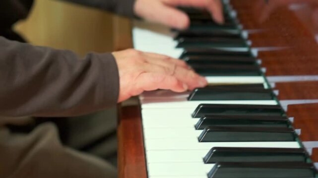 Close-up of hands playing a harmonium. Fingers move expressively over black and white keys -  conveying a calm and intimate atmosphere. Music -  and sound recording. -  practice -  creativity - 