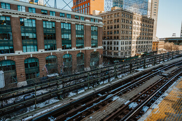 Elevated railway tracks in winter city. Snow-covered railway tracks passing between New York City buildings.