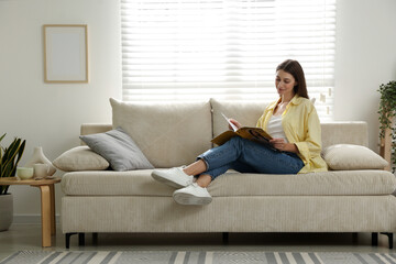 Obraz premium Woman with magazine relaxing near sofa at home, space for text