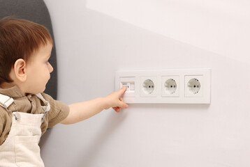 Child safety at home. Little boy playing with power outlet indoors © New Africa
