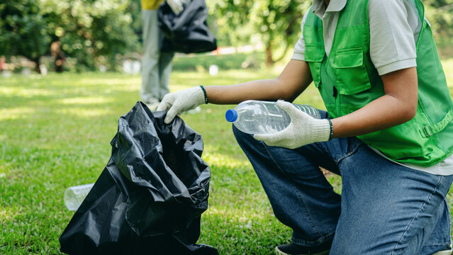 Volunteers collecting plastic bottles recycling waste environmental protection park cleanup community service green initiative sustainability outdoors
