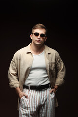 Obraz premium Fashion model. Handsome man in sunglasses posing against black background