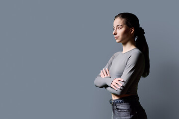 Portrait of beautiful serious young woman, 18-19 years old on gray background