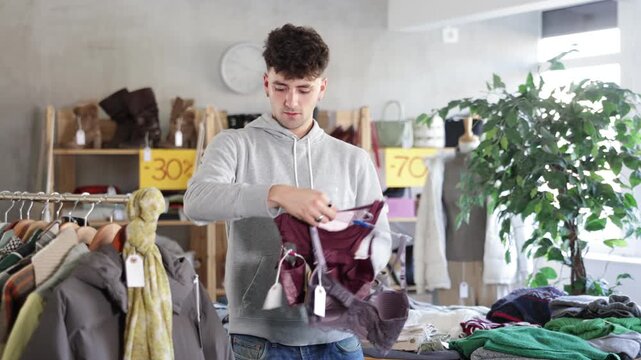 Young man buyer choosing lace women's underwear in clothing store