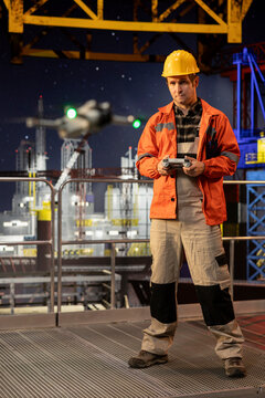 Industrial worker operates a UAV at a safe distance from offshore drilling platform, working with advanced aerial photography and mapping technology for inspection and maintenance. Oil rig.