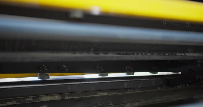 Metal offcut drops after cutting cycle on guillotine shear machine. Industrial manufacturing detail emphasizing physical labor and factory floor operations