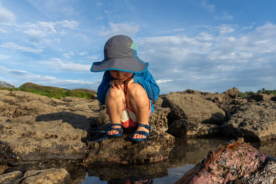 A young boy plays in tide pools at sunset on the coast in Costa Rica.