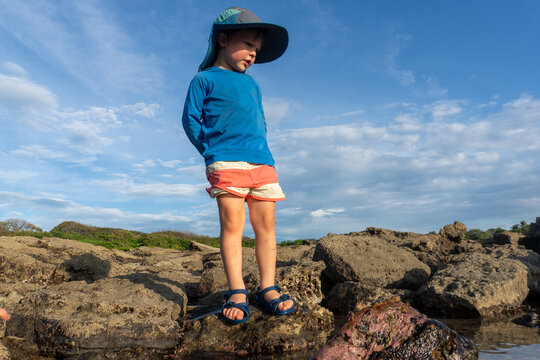 A young boy plays in tide pools at sunset on the coast in Costa Rica.
