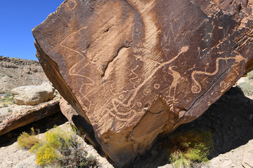 Ancient Kokopelli and snake petroglyphs on sandstone in Utah desert