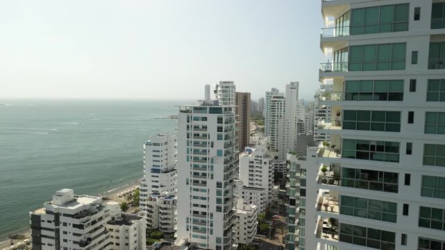 Cinematic aerial of modern city blocks meeting the coastline, creating a megacity postcard look.